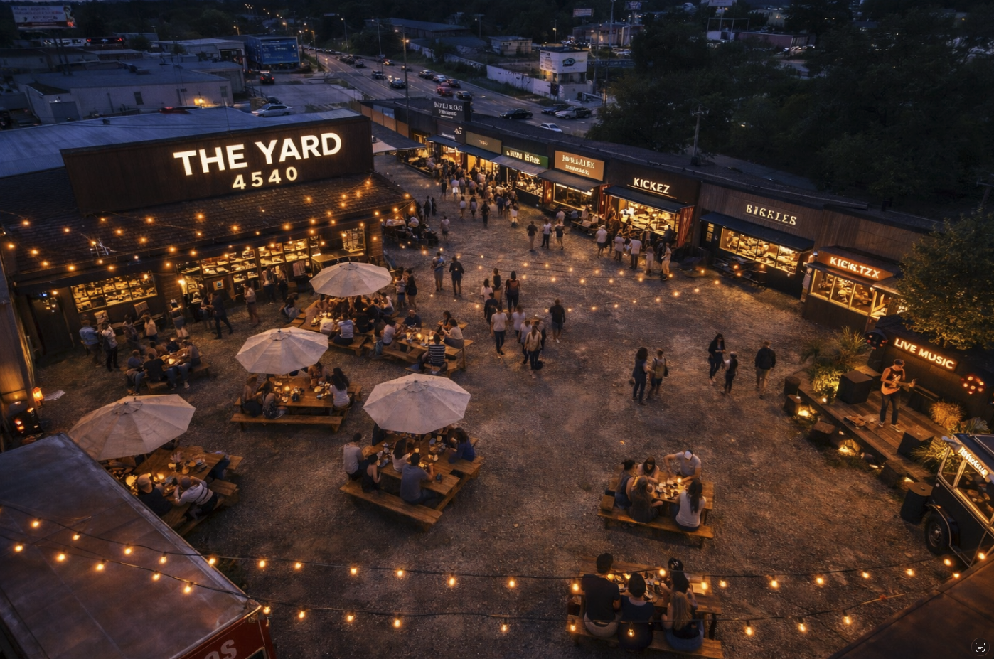 Aerial view of The Yard 4540 at night with illuminated sign, food trucks and crowds